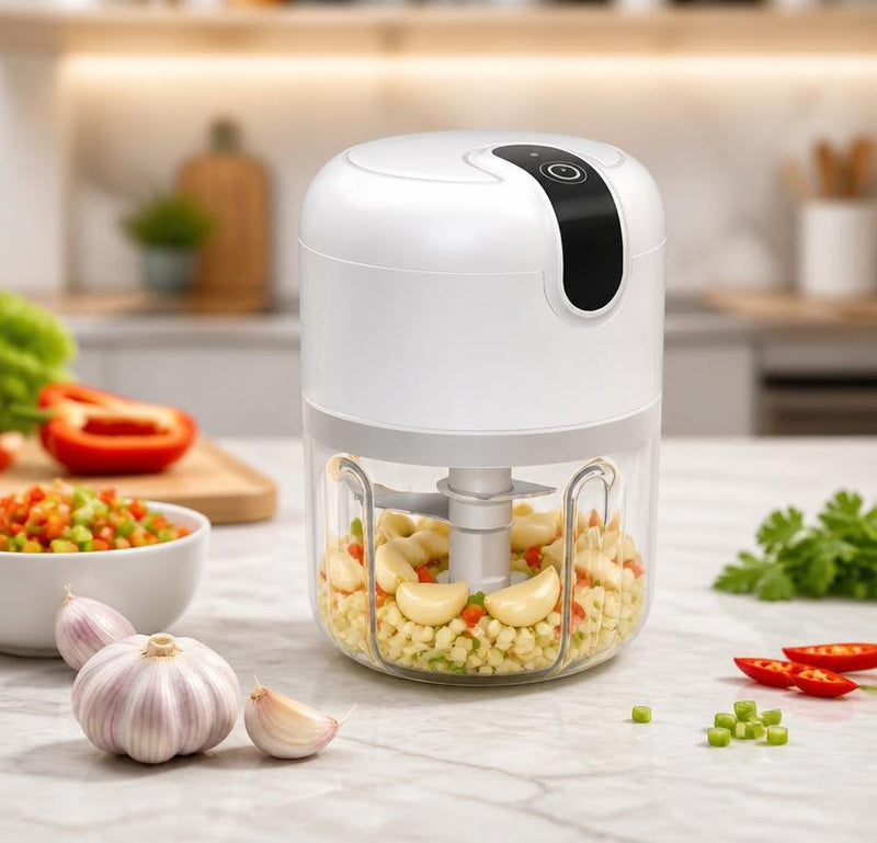 Mini electric chopper with garlic and vegetables on kitchen counter